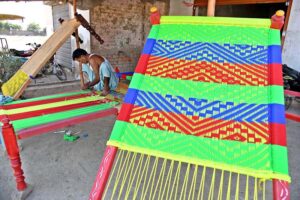 A worker busy in knitting traditional bed (charpai) at his workplace