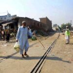 An old man is crossing a railway track while a train approaching may cause any mishap and needs the attention of concerned authorities near Sabzi Mandi