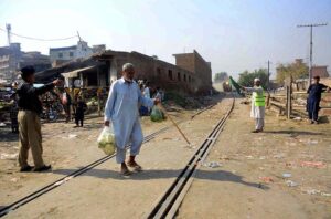 An old man is crossing a railway track while a train approaching may cause any mishap and needs the attention of concerned authorities near Sabzi Mandi