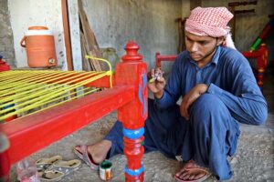 A worker busy in knitting traditional bed (charpai) at his workplace