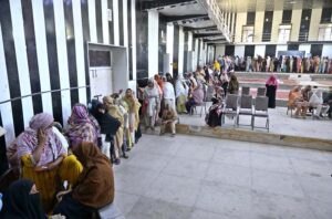 Deputy Director, BISP Raazia Yasmeen giving cash to deserving women at Benazir Income Support Program Quarterly Payment Distribution Center established at Company Bagh.