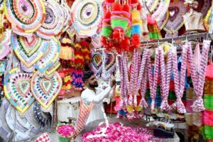 A vendor skillfully arranges fresh flower garlands at his shop in Larkana, attracting customers with colorful blooms.