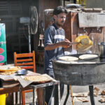 Vendor is busy preparing parathas for the customers at his roadside setup