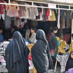 Women browse and purchase second-hand warm clothes at the weekly bazaar in Aabpara, Federal Capital, getting ready for the colder season