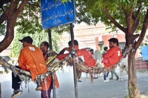 Railway coolies (porters) take a break on a hammock swing bed as they chat and wait for clients outside Lahore Railway Station.