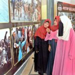 Female visitors are keenly viewing pictures exhibition of Kashmir Black Day at the Arts Council