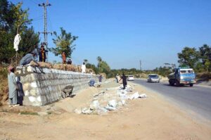 Laborers busy in construction work of wall along main road at District Mohmand Road