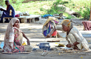 An elderly gypsy woman prepares a meal for her family in the open air on Thandi Sarak.