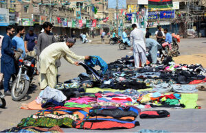 A vendor displaying and selling the covers of motorcycle to customers at Kohe noor chowk.