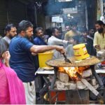 A vendor prepares traditional food item (tawa Qeema) to attract customers at roadside
