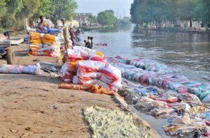 A large number of labourers are busy washing empty plastic bags in the canal