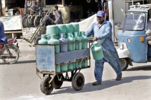 A laborer pushing a hand cart loaded with clean drinking water plastic bottles for supply in the market.
