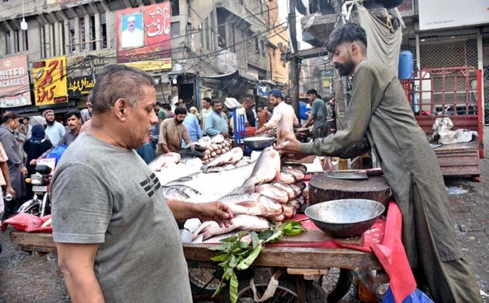 A vendor sells fish to attract customers outside his shop in a local market