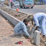 Laborers are busy fixing the cement blocks at the center path of the newly constructed Head Muhammad Wala Road