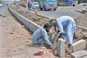 Laborers are busy fixing the cement blocks at the center path of the newly constructed Head Muhammad Wala Road