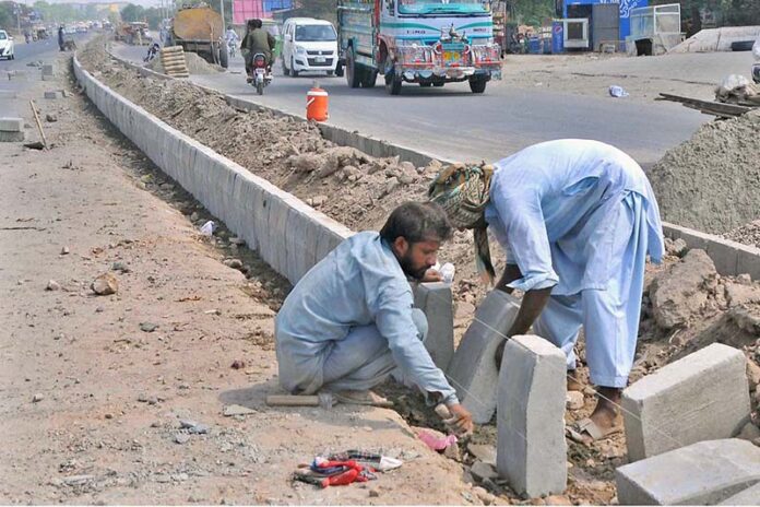 Laborers are busy fixing the cement blocks at the center path of the newly constructed Head Muhammad Wala Road