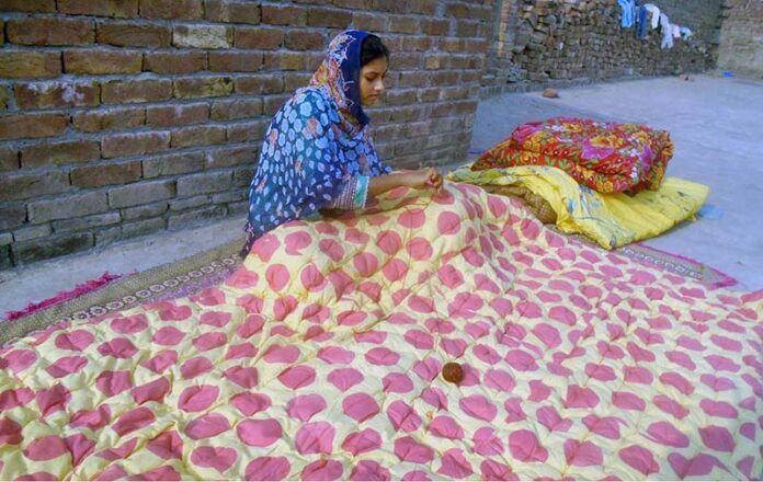 A young girl crafts quilts at her home to earn a livelihood for her family during the winter season