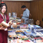 A participant at a book stall during the "2nd Annual Conference 2024 of Inter Boards Coordination Commission (IBCC) at Zaki Auditorium Allama Iqbal Open University
