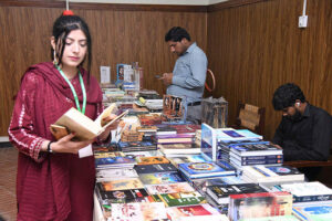 A participant at a book stall during the "2nd Annual Conference 2024 of Inter Boards Coordination Commission (IBCC) at Zaki Auditorium Allama Iqbal Open University