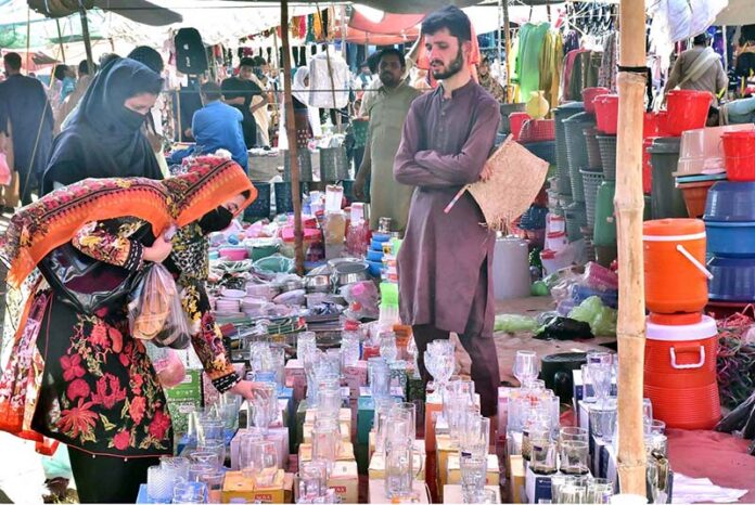 Women selecting and purchasing water glass from vendor at the Sunday Market