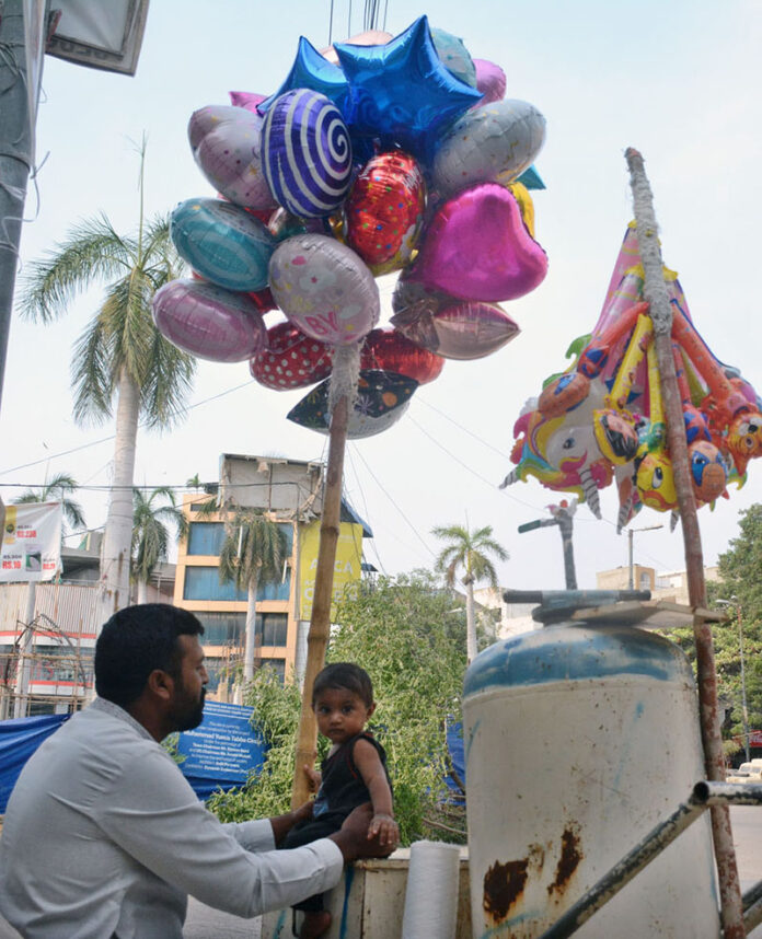 A vendor spends quality time with his child while managing his makeshift balloon-cart