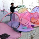 A vendor displaying nets to protect from mosquitoes bite to attract the customers at Jinnah Bagh Road