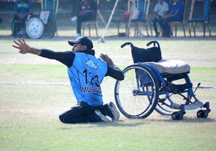 A fielder falls while attempting to catch the ball during the wheelchair cricket match between Balochistan and Sindh teams at the Interloop Quaid-e-Azam T-20 Cup Wheelchair Cricket 2024 at Bohran Wali Ground