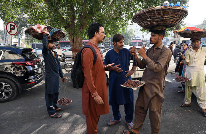 A street vendor sells dates on Mall Road, offering fresh date to passersby amidst the city