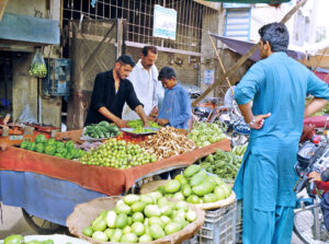 People buying vegetables from roadside stall.