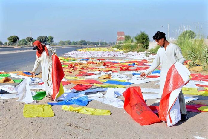 Labourers are busy spreading plastic bags for drying purpose after washing at the roadside