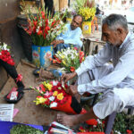 A vendor prepares fresh flowers bouquet to attract the customers at roadside his setup at Regal Chowk