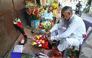 A vendor prepares fresh flowers bouquet to attract the customers at roadside his setup at Regal Chowk