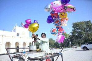 A street vendor fills gas into colorful balloons to attract children at GPO Chowk