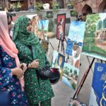 Visitors admire the artwork on display during the painting exhibition organized by the Knowledge Art Academy and Fortnight School System at the historic Wazir Khan Mosque