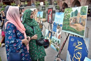 Visitors admire the artwork on display during the painting exhibition organized by the Knowledge Art Academy and Fortnight School System at the historic Wazir Khan Mosque