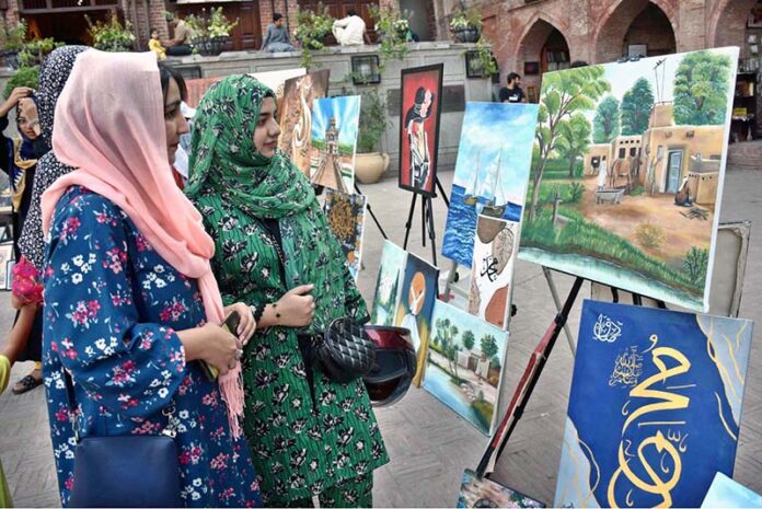 Visitors admire the artwork on display during the painting exhibition organized by the Knowledge Art Academy and Fortnight School System at the historic Wazir Khan Mosque