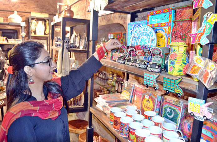 A Women browses and selects handcrafted decorative items especially truck art at a handicrafts shop near Delhi Gate