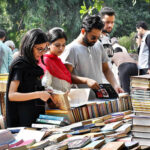 People selecting and purchasing old books from a roadside stall at Mall Road