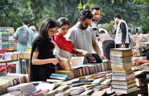 People selecting and purchasing old books from a roadside stall at Mall Road