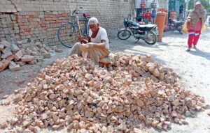 An elder labourer hard at work, breaking stones with a hammer for road construction in Bahawalpur during the development project in the city.