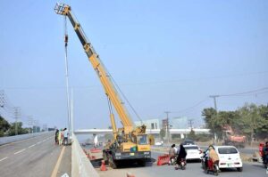 Labourers busy in work of flyover placing street light poles with the help of heavy machinery at Walton Road.