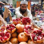 Vendor arranging and displaying pomegranate to attract the customers at Kohati Chowk