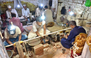 Labourers busy in preparing the design on the bangles with the help of machine at their workplace.