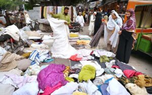 Women selecting and purchasing old clothes pieces from roadside vendor at Kohati area