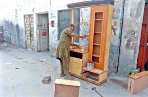 An elder labourer hard at work, breaking stones with a hammer