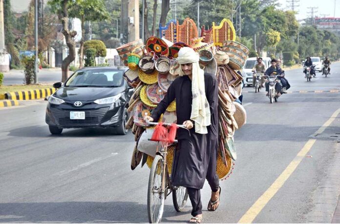 A street vendor wanders the roads, selling handicraft items from his bicycle to earn livelihood in the federal capital