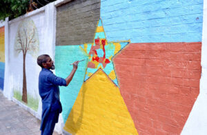 An artist passionately creating stunning paintings to beautify the walls of Government Kinnaird High School that attracts and inspires students.