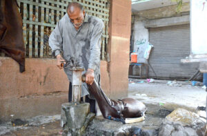 A man fills his goatskin container with water from a vintage British-era hand pump in the Saddar area.