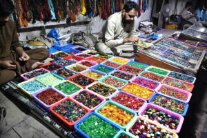 A vendor displaying and arranging ring stones to attract the customers at his roadside setup in a local market.