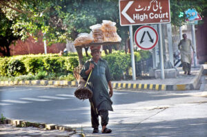 Wandering the city streets,a vendor carries a delicious selection of traditional snacks on his head to sell.